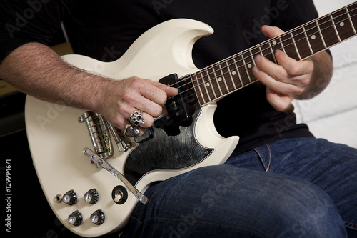 Close-up of mid adult man's torso playing guitar