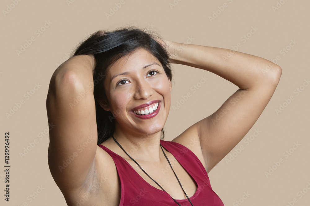 Beautiful young woman with hands in hair over colored background Beautiful young woman with hands in hair over colored background