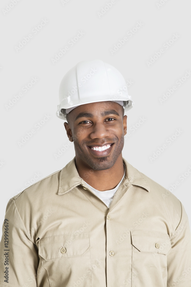 Portrait of happy young African male construction worker over gray background Portrait of happy young African male construction worker over gray background