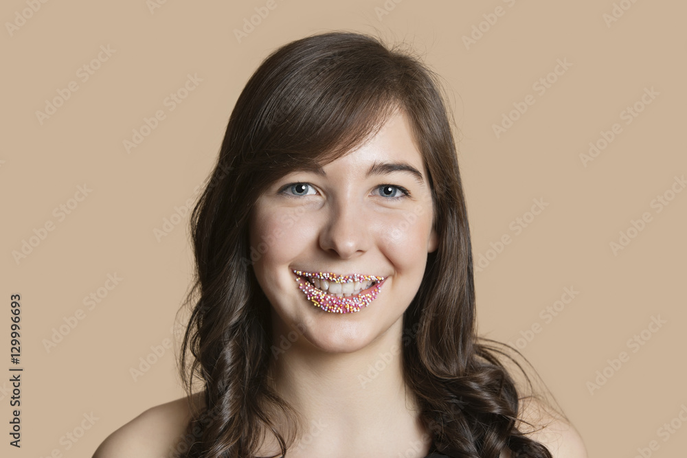 Portrait of a happy young woman with sprinkled lips over colored background Portrait of a happy young woman with sprinkled lips over colored background