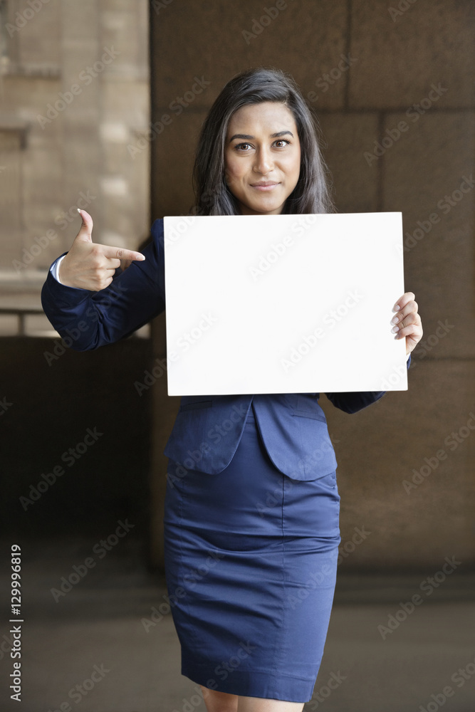 Portrait of a young Indian businesswoman pointing towards sign Portrait of a young Indian businesswoman pointing towards sign