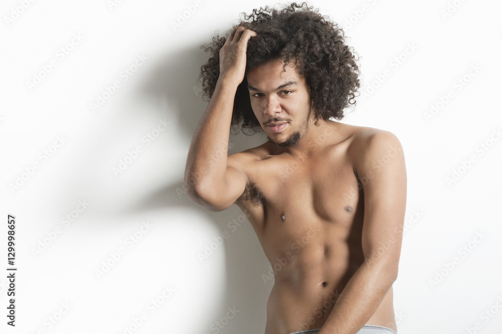 Fototapeta premium Portrait of young man with posing with hand in hair over white background