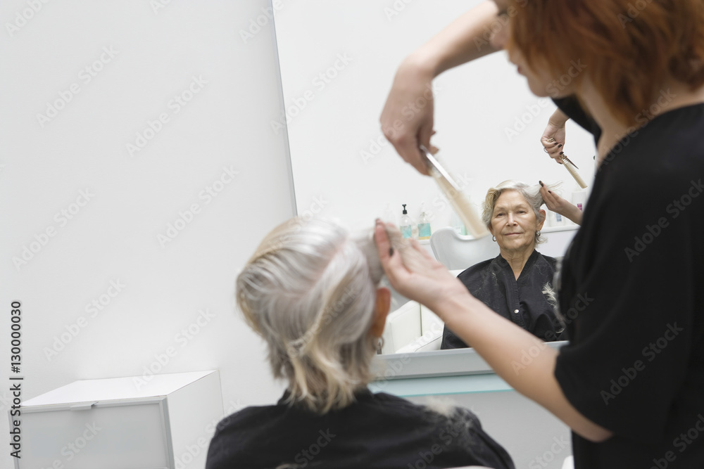 Senior woman getting haircut from female hairdresser in salon Senior woman getting haircut from female hairdresser in salon