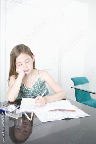 Young girl doing homework at desk in house © moodboard