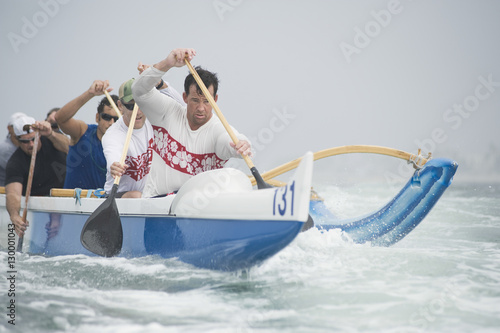Confident male rower with team paddling outrigger canoe in race photo
