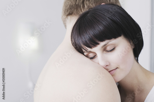 Closeup side view of beautiful young woman embracing shirtless man