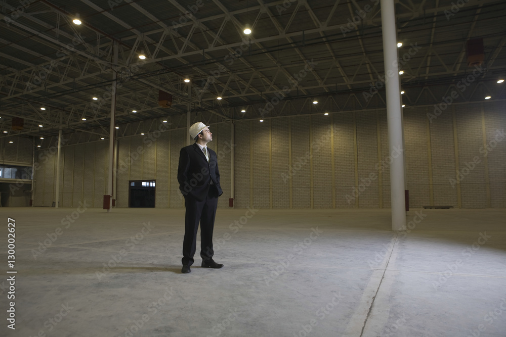 Full length of male architect looking away in empty warehouse Full length of male architect looking away in empty warehouse