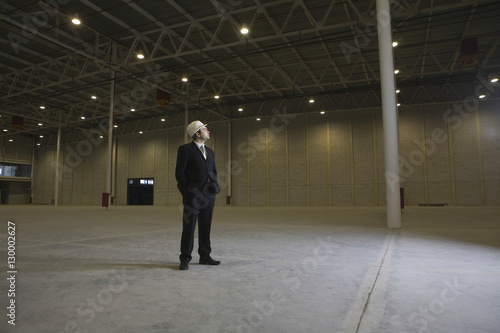 Full length of male architect looking away in empty warehouse
