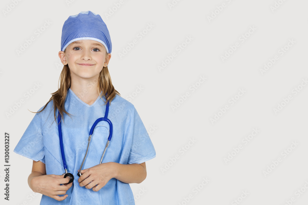 Portrait of young girl in surgeon's costume against gray background Portrait of young girl in surgeon's costume against gray background
