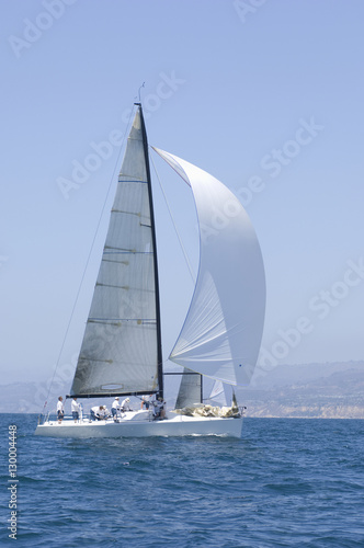 Sailboat racing in the blue and calm ocean against sky