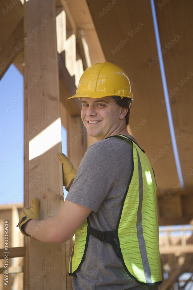 Portrait of a happy laborer positioning plank of wood at construction site Portrait of a happy laborer positioning plank of wood at construction site