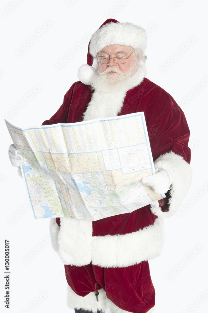 Man dressed in Santa Claus reading road map isolated over white background Man dressed in Santa Claus reading road map isolated over white background