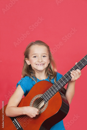 Portrait of girl playing guitar against red background