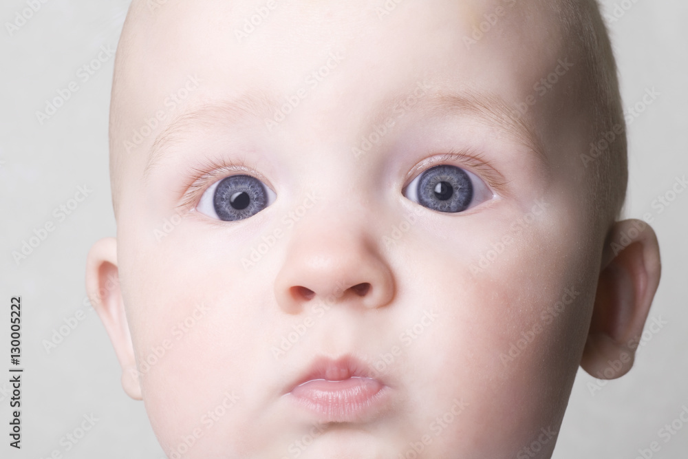 Closeup portrait of adorable baby boy with blue eyes on white background