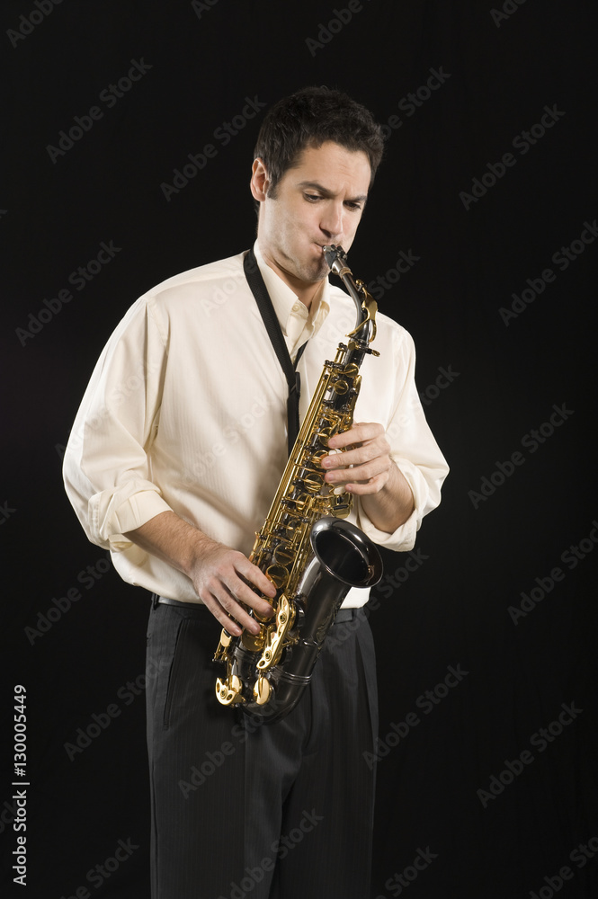 Fototapeta premium Man playing saxophone isolated over black background