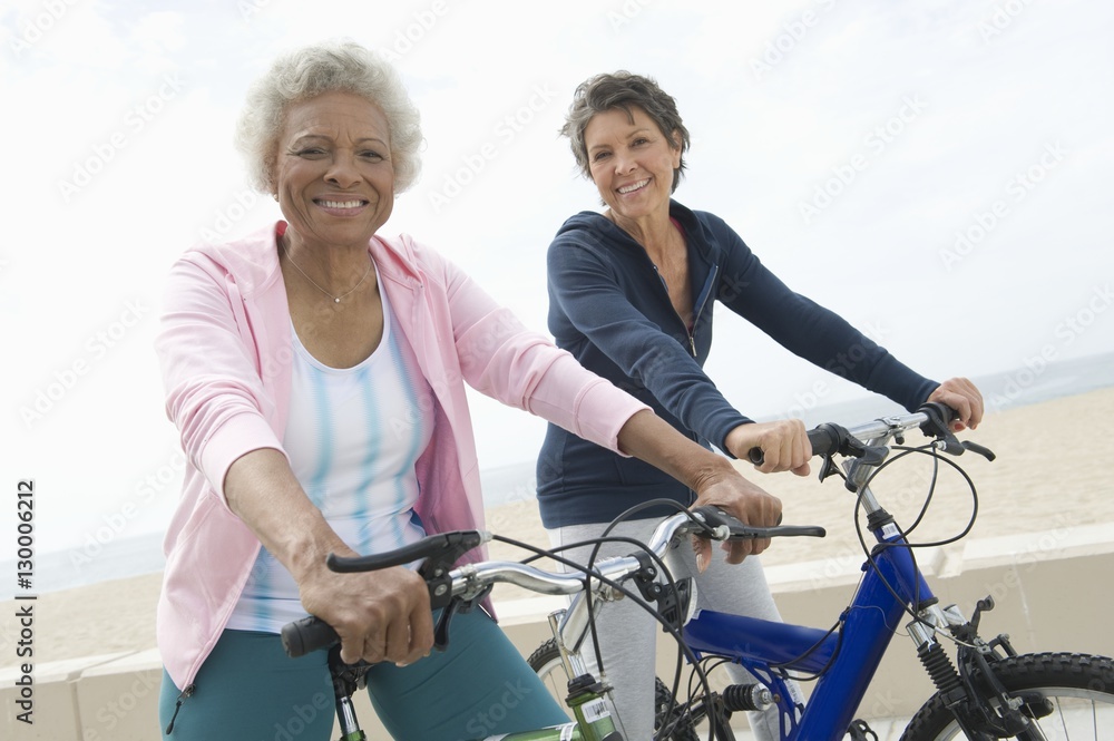 Obraz premium Portrait of happy senior multiethnic female friends riding bicycles together