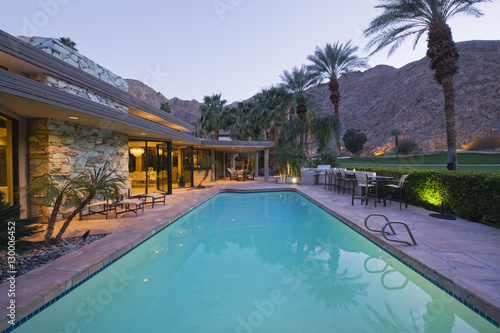 View of swimming pool and illuminated modern home exterior