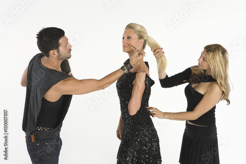 Two fashion artists assisting young female model isolated over white background