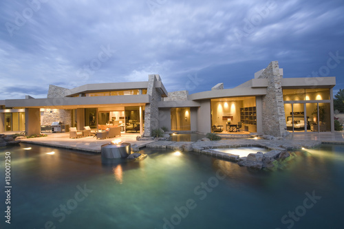 Swimming pool and illuminated modern house exterior against the sky