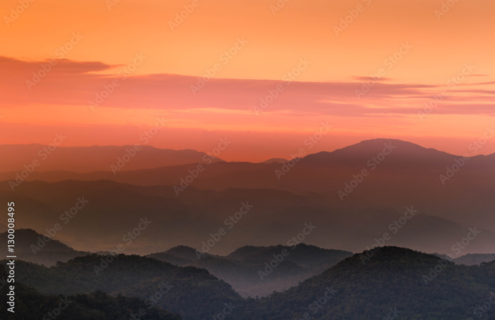 Orange and pink twilight  sunset with layers of mountains silhou