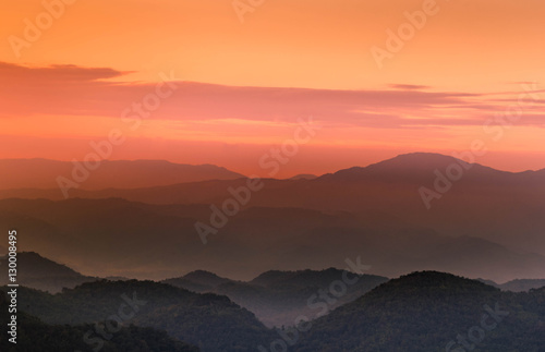 Orange and pink twilight sunset with layers of mountains silhou