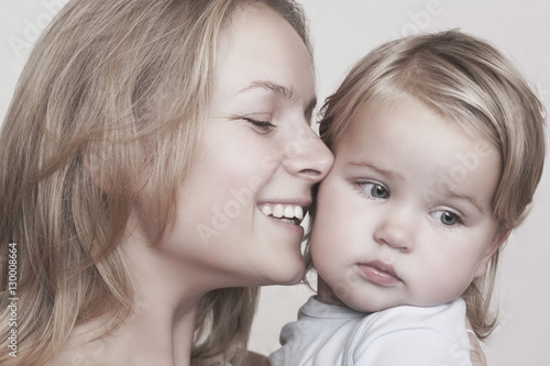 Closeup of smiling young mother caressing baby girl over colored background