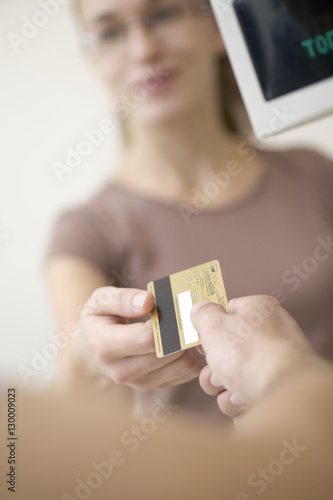 Young woman passing over a credit card to salesclerk in store