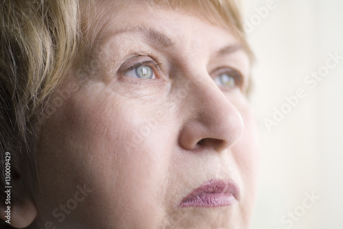Closeup of senior woman looking away over colored background