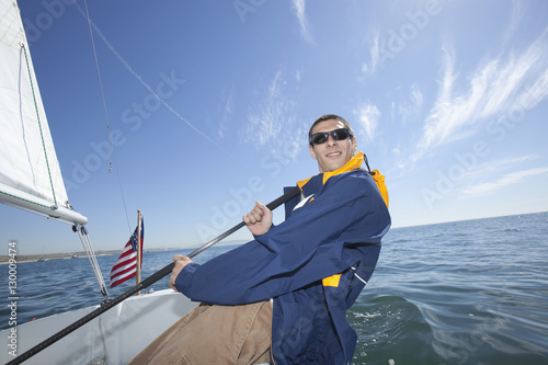 Happy young mixed race man sailing in boat
