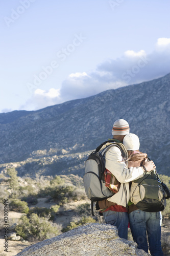 Rear view of a young couple in warm clothing looking at mountain view