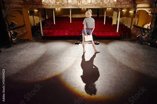 Fototapete Full length of a young woman with script rehearsing on stage