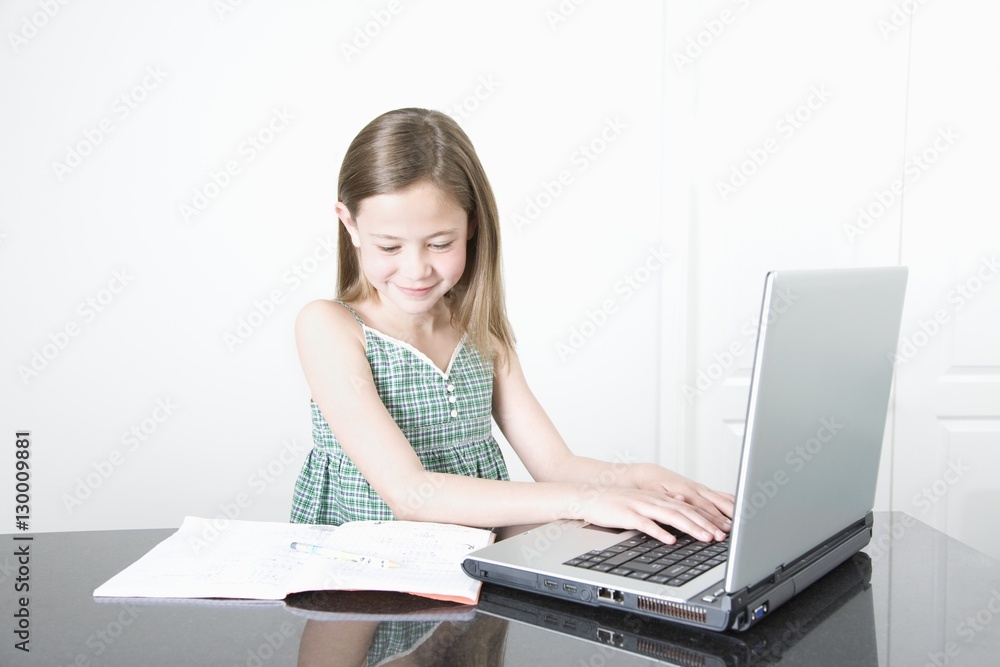 Smiling young girl using laptop on desk at home Smiling young girl using laptop on desk at home