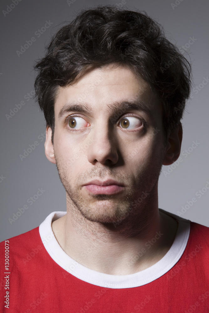 Fototapeta premium Suspicious young male looking sideways isolated over grey background