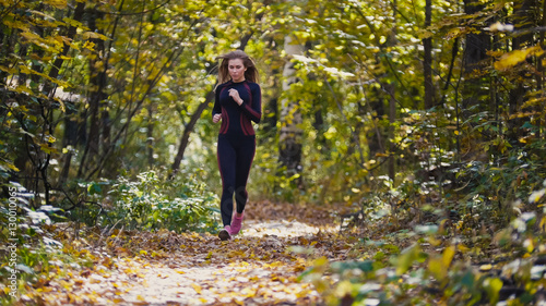 Young active female athlete exercising outdoor autumn park. Healthy women