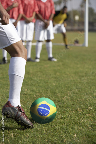 Fototapeta Naklejka Na Ścianę i Meble -  Soccer players preparing for a free kick in front of Brazilian flag