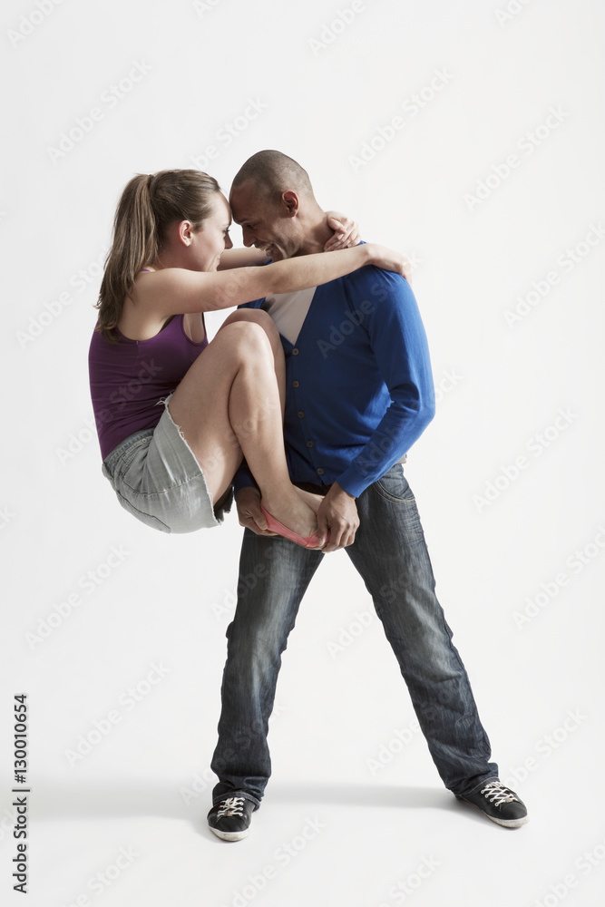 Full length of young man supports modern dance partner over white
