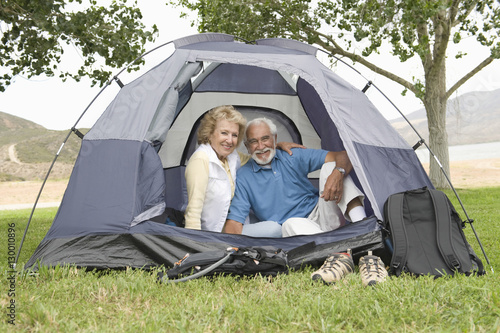 Portrait of a smiling senior couple sitting at entrance to tent