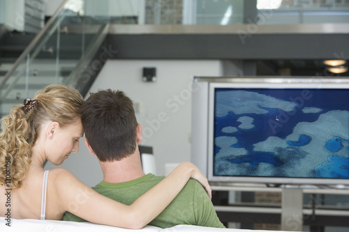 Rear view of young couple watching television in living room