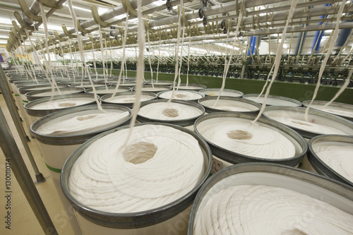 Rolls of fabric and machinery in spinning factory 