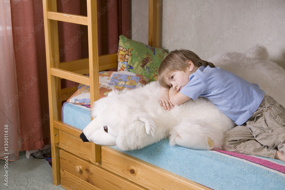 Thoughtful young boy with polar bear soft toy lying on bunk bed Thoughtful young boy with polar bear soft toy lying on bunk bed