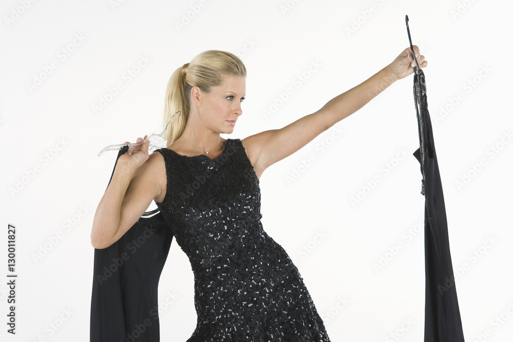 Φωτογραφία Young female model choosing a dress to wear isolated over white background