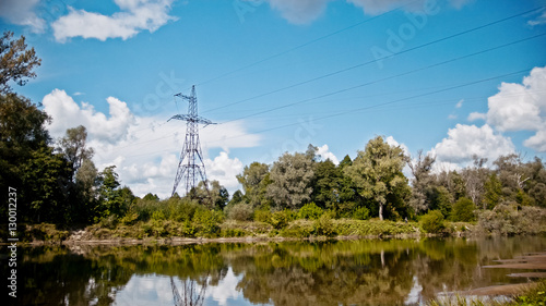 Wide shot timelapse of electricity power lines and high voltage pylons on a field in the countryside at summer near river