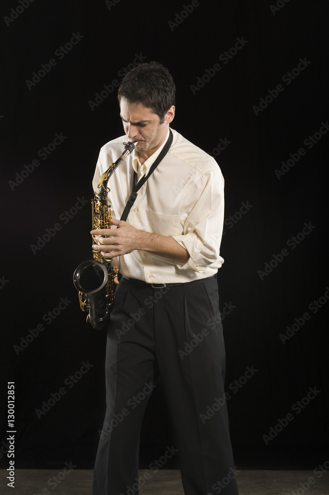 Naklejka premium Caucasian man blowing saxophone isolated over black background