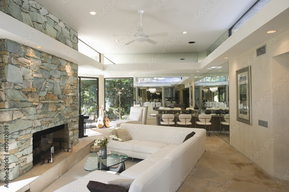 Sunken seating area and stone fireplace with dining area in background at home - obrazy, fototapety, plakaty 