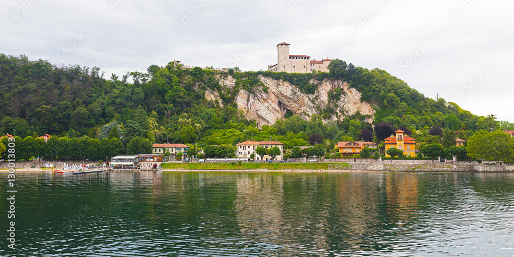 Fototapeta premium Town buildings on a hilly shore of Lake Como, Italy. Summer landscape with cloudy sky and buildings reflection in the lake waters.