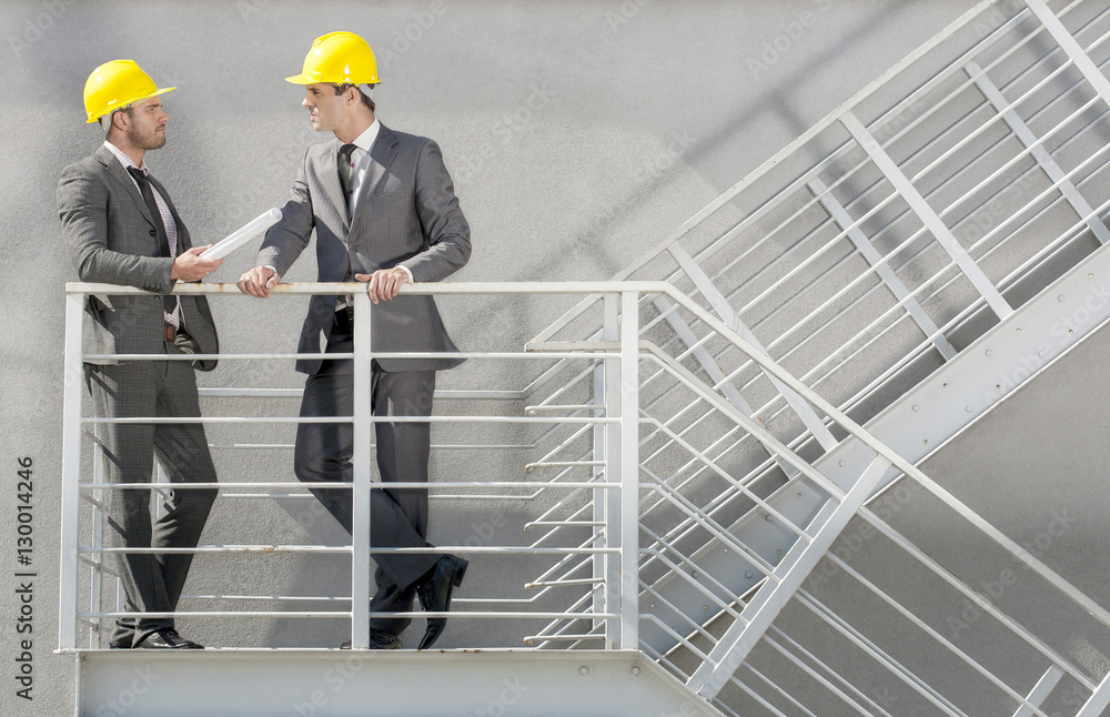 Full length of young male architect discussing on stairway Full length of young male architect discussing on stairway