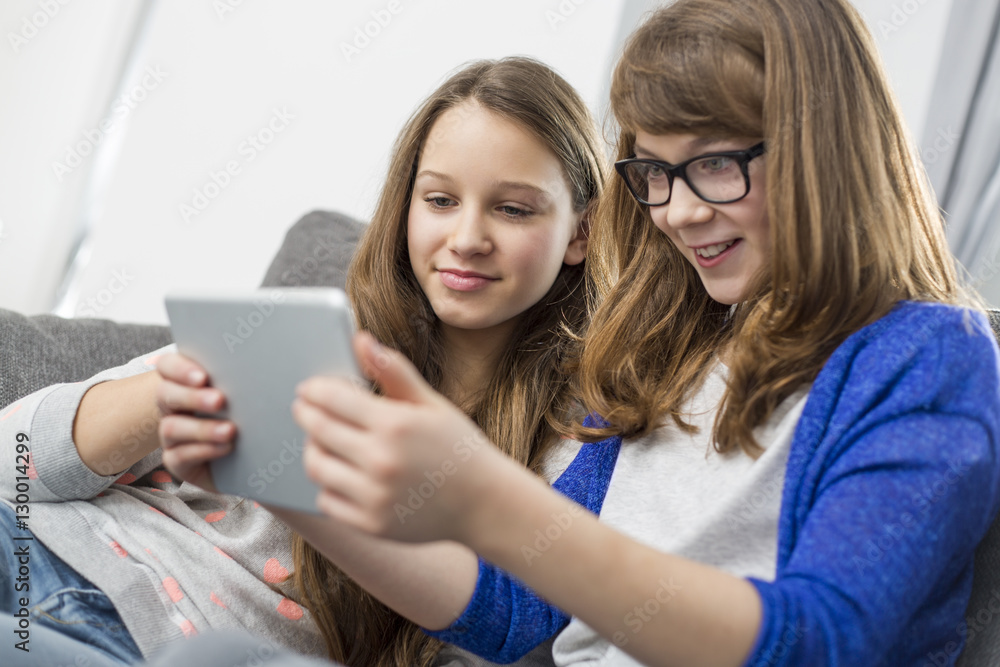 Sisters using digital tablet together at home Sisters using digital tablet together at home