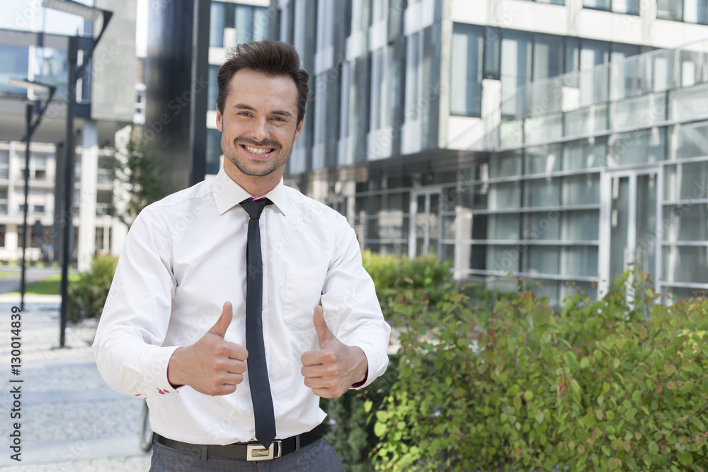 Portrait of confident businessman showing thumbs up outside office building Portrait of confident businessman showing thumbs up outside office building