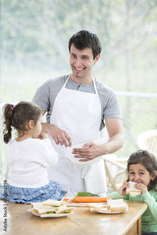 Happy father preparing food with little daughters at home Happy father preparing food with little daughters at home