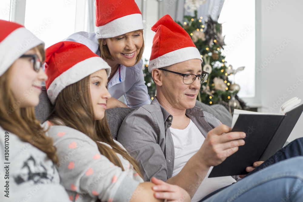 Father reading book for family at home during Christmas Father reading book for family at home during Christmas